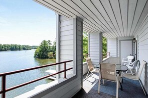 A balcony with a view of a lake, a table with chairs, and a railing. - Beautiful lakefront home w/free WiFi, full kitchen, shared pool & hot tub (Wisconsin Dells)