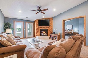 A living room with a fireplace, a ceiling fan, and a television. - Beautiful lakefront home w/free WiFi, full kitchen, shared pool & hot tub (Wisconsin Dells)