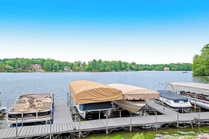A dock with covered boats and a lake view. - Beautiful lakefront home w/free WiFi, full kitchen, shared pool & hot tub (Wisconsin Dells)