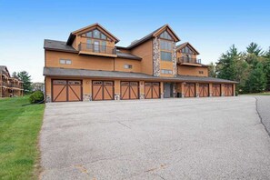 A large wooden building with multiple garage doors, a balcony, and a stone column.