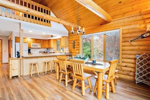 A log cabin interior with a dining area, kitchen, and a loft bedroom. - Secluded, dog-friendly home with tree-lined view, firepit, fireplace, & deck (Friendship)