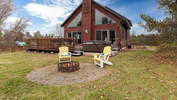 Een houten hut met een ruim terras, twee Adirondack-stoelen en een vuurkuil.