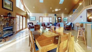 Een ruime woonkamer met een open haard, een houten eettafel en comfortabele zithoek.