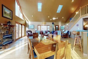 A spacious living room with a fireplace, wooden dining table, and comfortable seating. - Charming Golf View Home, w/ Hot tub, Sauna, Fire pit, near Lakes & Trails! (Nekoosa)