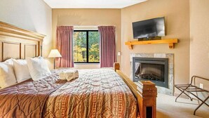 Ett hotellrum med en säng, en tv, en öppen spis och ett fönster med gardiner.