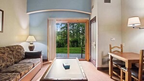 A room with a sofa, a table, a lamp, and a view through a glass door to an outdoor area. - Cozy Fireside Condo with Jetted Tub & AC (Wisconsin Dells)