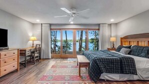 A bedroom with a bed, desk, chair, and a view of the outdoors. - Lakefront home w/ deck, grill, fireplace, firepit, AC, & WiFi (Eagle River)