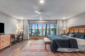 Un dormitorio con cama, escritorio, silla y vistas al exterior.