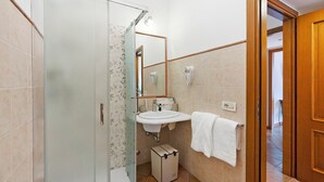 Une salle de bain avec une douche à parois de verre, un lavabo avec un miroir et un porte-serviettes.