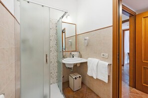 Ein Badezimmer mit Duschkabine aus Glas, Waschbecken mit Spiegel und Handtuchhalter.