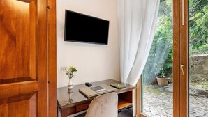 Un bureau en bois, un téléviseur à écran plat, un vase avec des fleurs, un carnet et une télécommande.