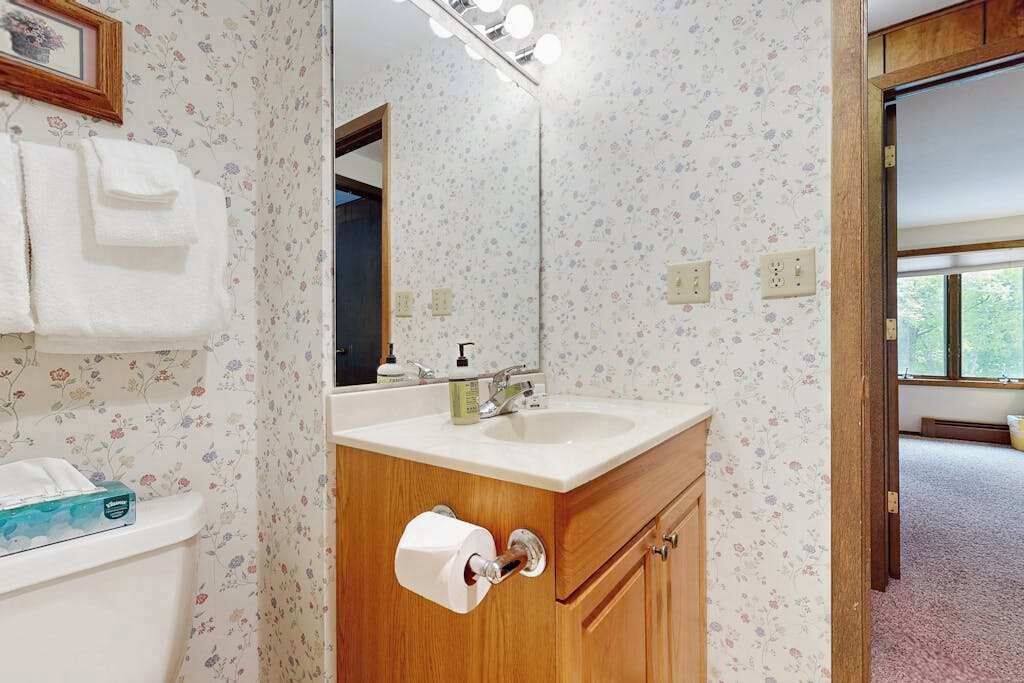 Une salle de bain équipée de toilettes, d’un lavabo, d’un miroir et de serviettes.