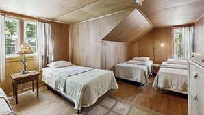 Ein Zimmer mit drei Betten, Holzwänden und einer schrägen Decke.