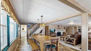 Ein großzügiger Wohnbereich mit einem Holzesstisch, einer Bank und einem Sofa. Eine Treppe führt zu einer weiteren Ebene, und ein Fernseher ist an der Wand montiert.