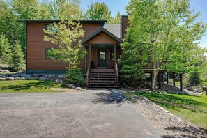A modern log cabin with a front porch, a stone pathway, and a well-maintained yard. - Lakefront lodge with private dock, firepit, deck & sunset views (Eagle River)