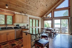 A spacious kitchen with wooden cabinets, a stone island, and large windows. - Lakefront lodge with private dock, firepit, deck & sunset views (Eagle River)