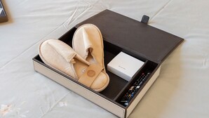 A pair of slippers, a remote control, and a box on a bed. - Villevieille Relais – Superior Double Room with Sea View, Wi-Fi & Air Conditioning (Piano di Sorrento)