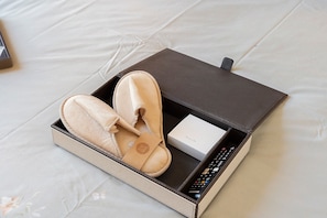 A pair of slippers, a remote control, and a box on a bed. - Villevieille Relais – Superior Double Room with Sea View, Wi-Fi & Air Conditioning (Piano di Sorrento)
