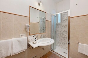 Ein Badezimmer mit Waschbecken, Spiegel, Handtuchhalter und Dusche.
