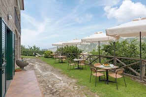 Eine Terrasse im Freien mit Tischen und Stühlen, umgeben von einem Kiesweg und einem Holzzaun.