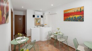 A dining area with a small kitchen, a painting on the wall, and a door leading to another room. - Villevieille Relais – Superior Double Room with Sea View, Wi-Fi & Air Conditioning (Piano di Sorrento)