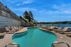 Ein Pool mit Liegestühlen, eine Steinmauer und Blick auf die umliegende Landschaft.
