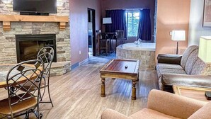 Ein Wohnzimmer mit Kamin aus Stein, einem flachbildfernseher darüber, einem Billardtisch und einem Sofa.