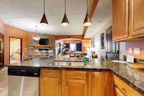 A kitchen with granite countertops, wooden cabinets, a dishwasher, and pendant lighting. - Spacious Chula Vista Stay | Dells Adventure Access (Wisconsin Dells)