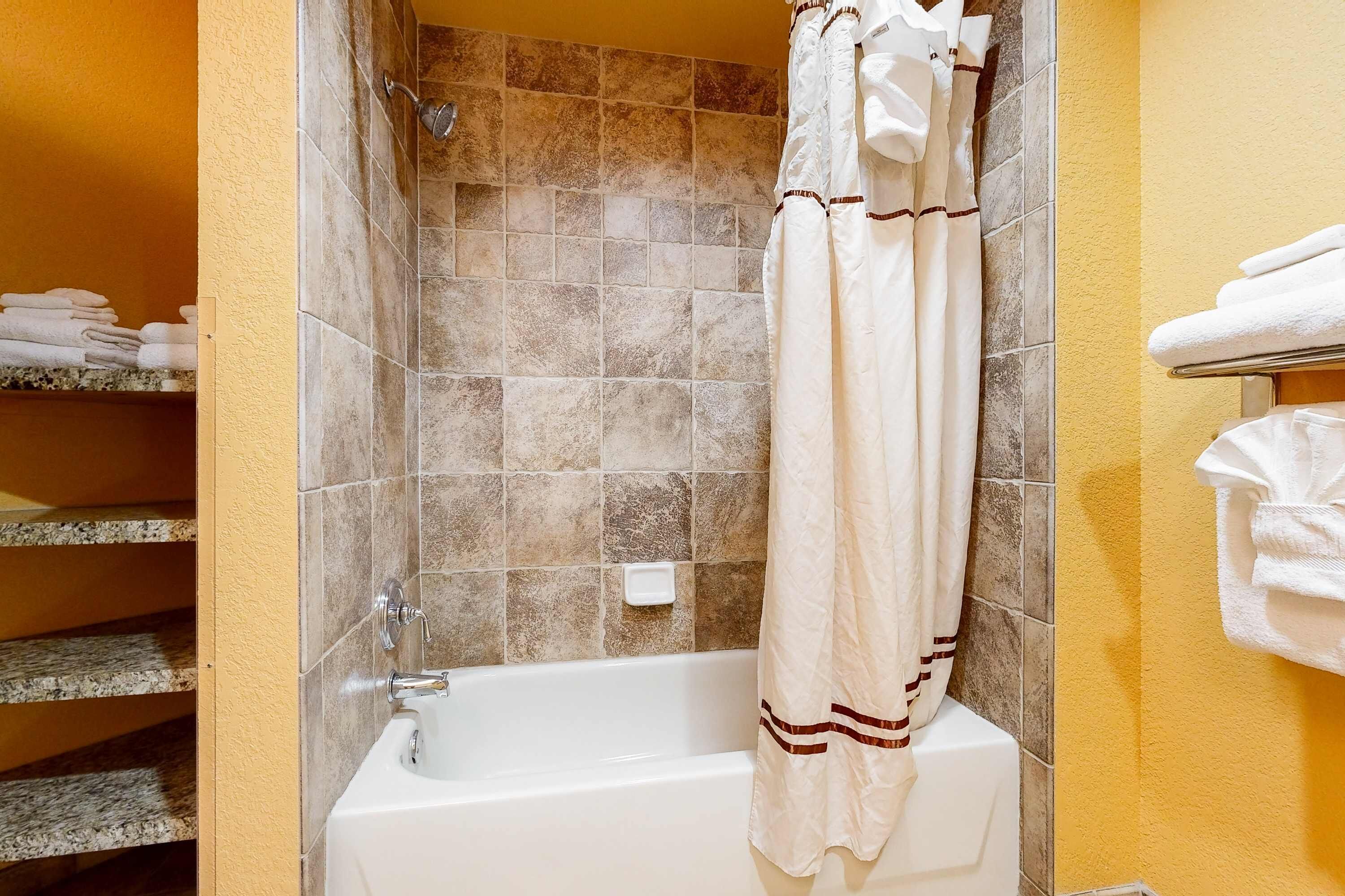 A bathroom with a bathtub, tiled walls, and a shower curtain.