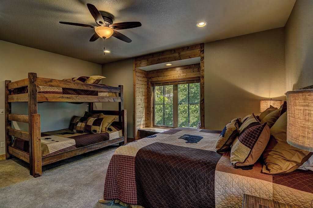 Un dormitorio con literas, una cama individual, un ventilador de techo y una ventana con vistas.