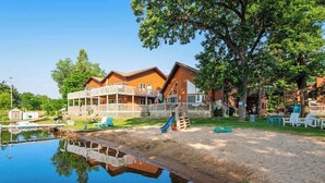 A wooden cabin with a pool, a slide, and a fenced playground area.