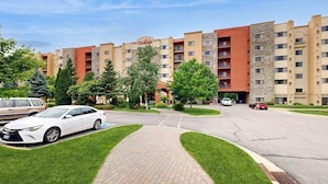 Et hotel med en central gårdsplads, parkeringsplads og en bygning med flere etager og altaner.