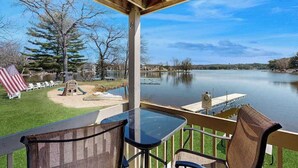 Une terrasse au bord du lac, avec une table et des chaises, un petit espace de jeux et une jetée qui s’avance dans l’eau.