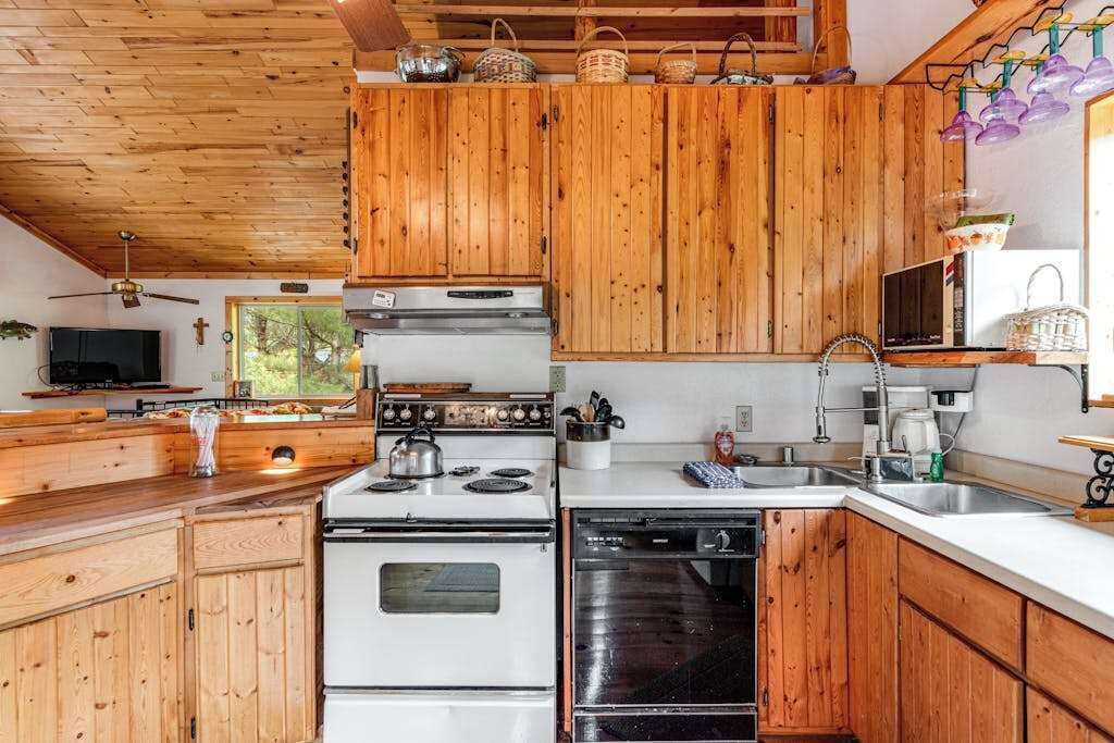 Une cuisine avec des meubles de rangement en bois, une cuisinière, un lave-vaisselle et un évier.