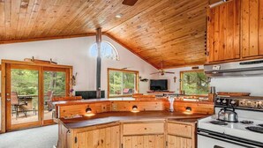 Une cuisine avec des meubles en bois, une cuisinière et un coin repas comprenant une table et des chaises.