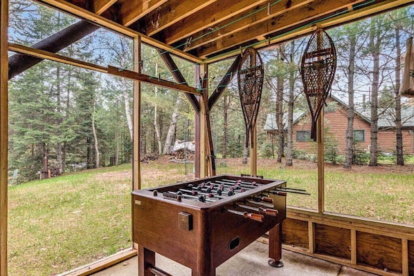 A wooden-floored room with a large window overlooking a forested area.