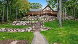 A lodge with a stone pathway leading to a wooden building surrounded by trees. - 3-story chalet with private hot tub, game room & waters toys - dog-friendly (Lac Du Flambeau)