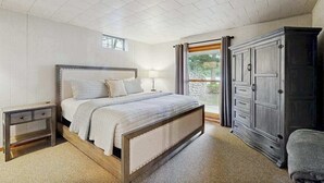 Een slaapkamer met een bed, nachtkastjes, een kledingkast en een raam met gordijnen.
