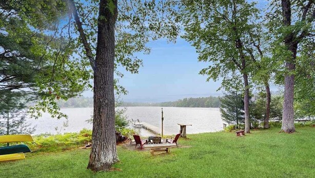 Een terras aan het water met een bank, stoelen en een tafel.