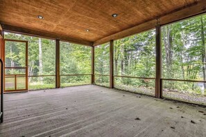 A spacious room with large windows, a wooden ceiling, and a concrete floor.