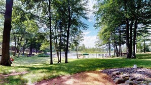 Un parc avec un sentier de terre, des arbres et une étendue d’eau en arrière-plan.