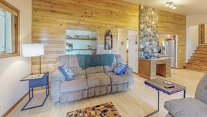 Un salon comprenant un canapé, une table basse, une lampe et un tapis. Il y a également un coin cuisine avec un réfrigérateur et une cuisinière.