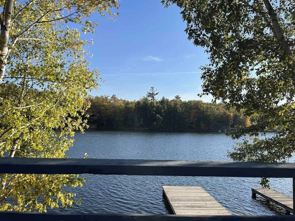 Un lago con un muelle de madera y árboles al fondo.