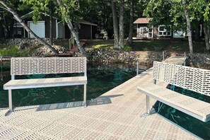 Zona de piscina con dos bancos blancos y un muro de piedra.