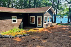A cabin with a porch, a small deck, and a view of a lake. - Dog-friendly lakefront hideaway with docks, firepit, fireplace & W/D (Minocqua)
