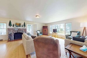 A living room with a stone fireplace, two sofas, a coffee table, and a television on a stand. - Lakefront home with large patio, docks, gas grill, fire pit, & WIFI (Phelps)