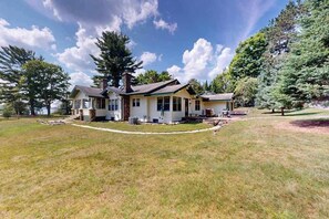 A two-story house with a front porch, a chimney, and a well-maintained lawn. - Lakefront home with large patio, docks, gas grill, fire pit, & WIFI (Phelps)