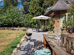 Un patio con una parrilla, mobiliario exterior y un sendero de piedra.