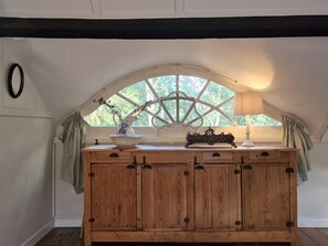 A wooden cabinet with drawers, a decorative pitcher, and a lamp on a windowsill. - Historic Romantic Pavilion Retreat for 4 (Rendeux)