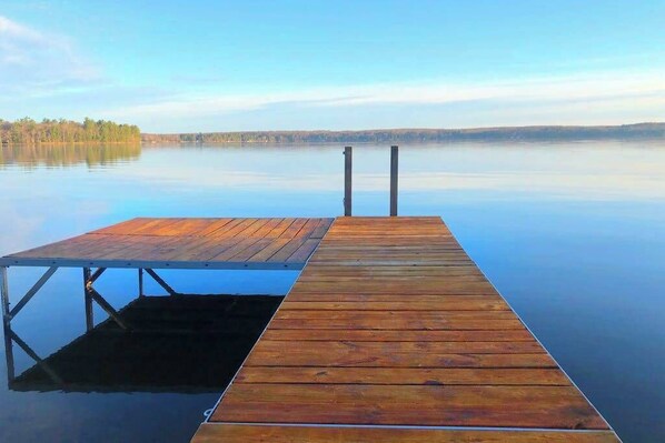A wooden dock extending into calm water with a clear sky above.